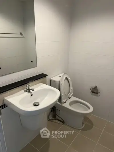 Modern bathroom with sleek white fixtures and tiled walls, perfect for a contemporary home.
