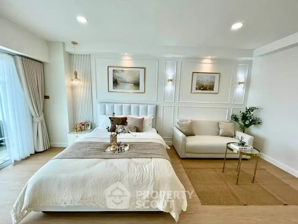 Luxurious bedroom with elegant decor and natural light, featuring a cozy bed and stylish sofa.