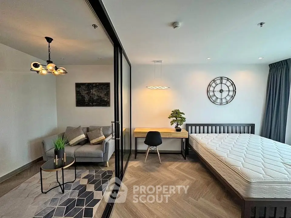 Modern bedroom with stylish decor, featuring a cozy sitting area and sleek wooden flooring.