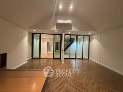 Spacious modern living room with elegant wooden flooring and glass partition.