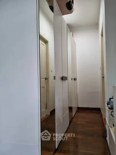 Spacious hallway with sleek white wardrobes and wooden flooring, perfect for modern storage solutions.