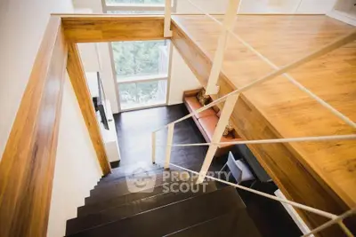 Modern loft-style living room with wooden floors and large windows offering natural light.