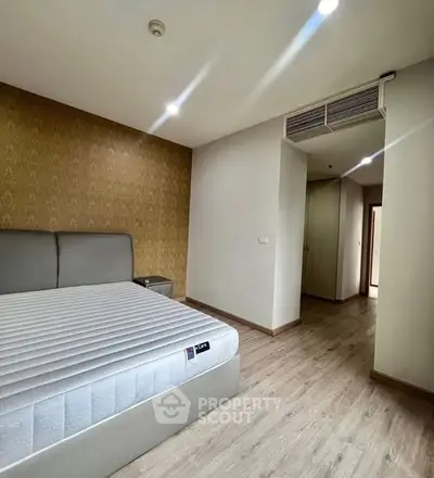 Spacious bedroom with modern design and elegant wallpaper accent wall.