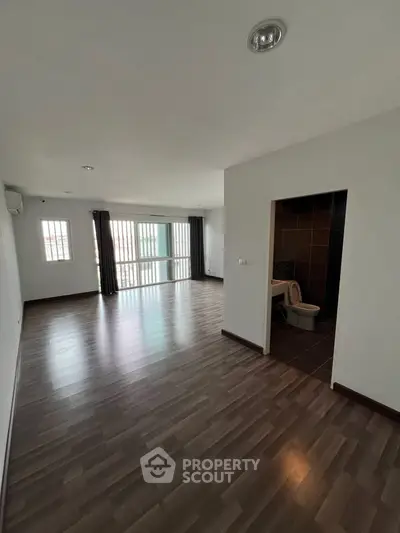 Spacious open-plan living area with modern flooring and natural light, featuring a convenient bathroom.
