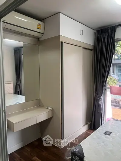 Modern bedroom with sleek wardrobe, air conditioning, and elegant curtains, offering a cozy and stylish living space.