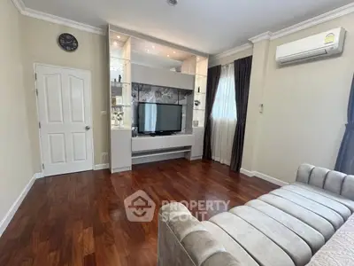Elegant living room with hardwood floors, modern TV unit, and plush sofa in a cozy apartment.