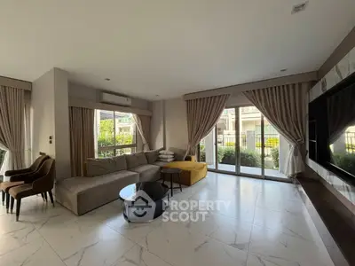Spacious living room with modern decor, large windows, and garden view, perfect for relaxation and entertaining.