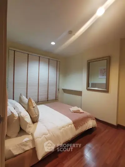 Cozy bedroom with wooden flooring and soft lighting, featuring a comfortable bed and stylish decor.