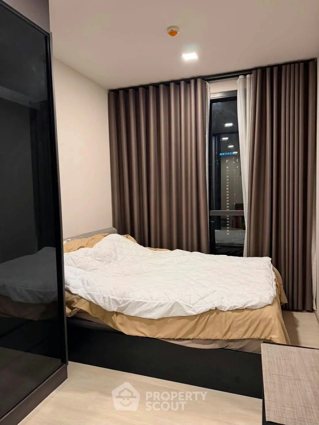 Modern bedroom with large window and stylish curtains in a contemporary apartment.