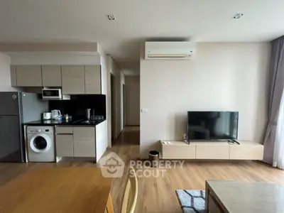 Modern living room with open kitchen, featuring sleek appliances and stylish decor.