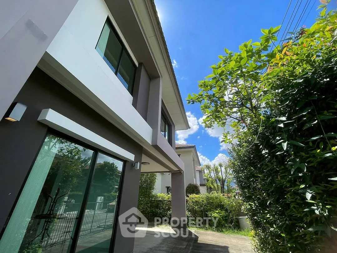 Modern two-story house with lush greenery and clear blue sky