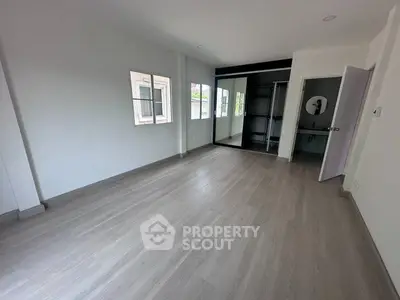 Spacious empty room with large windows and mirrored closet, perfect for customization.
