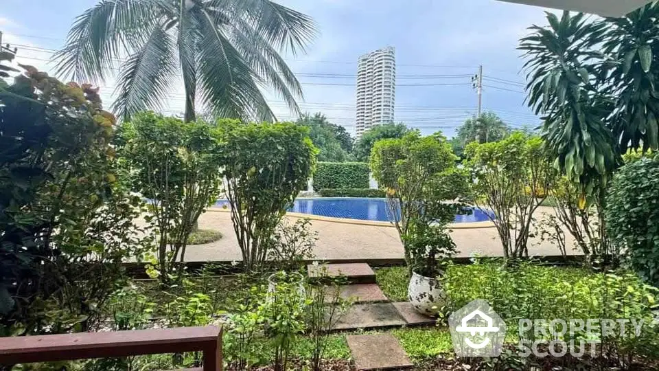 Lush garden view with pool and high-rise building in the background