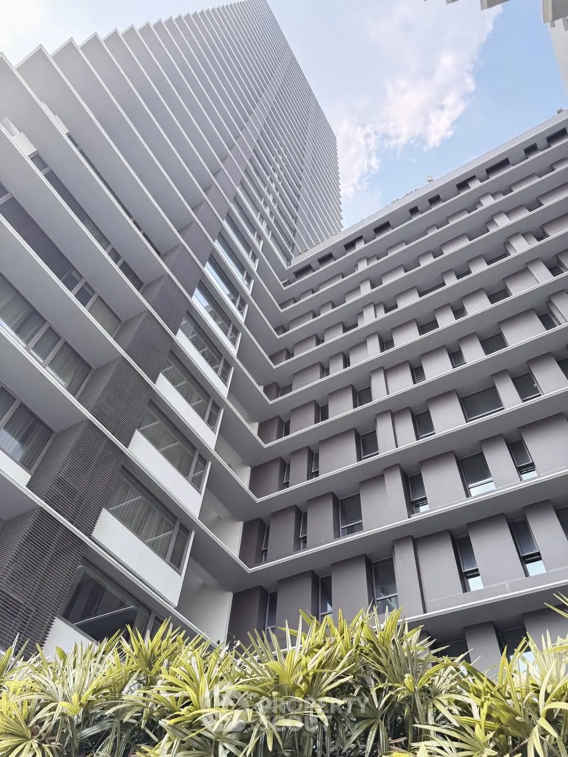 Modern high-rise building with sleek architecture and lush greenery