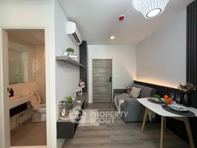 Modern living room with cozy decor and open bathroom view, featuring stylish furniture and elegant lighting.