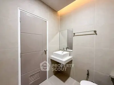 Modern bathroom with sleek design and neutral tones, featuring a wall-mounted sink and mirror.