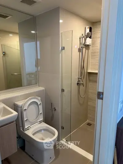 Modern bathroom with glass shower and sleek fixtures in contemporary apartment.