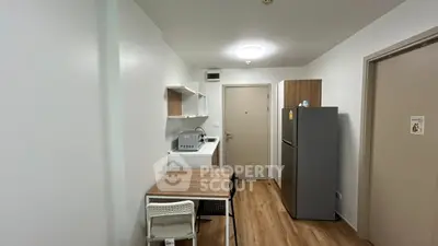 Compact kitchen with dining area in modern apartment, featuring wooden flooring and sleek appliances.
