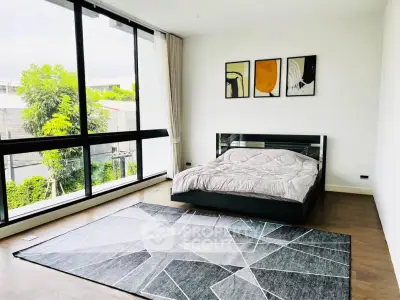 Spacious bedroom with large windows and modern decor in a luxury apartment.