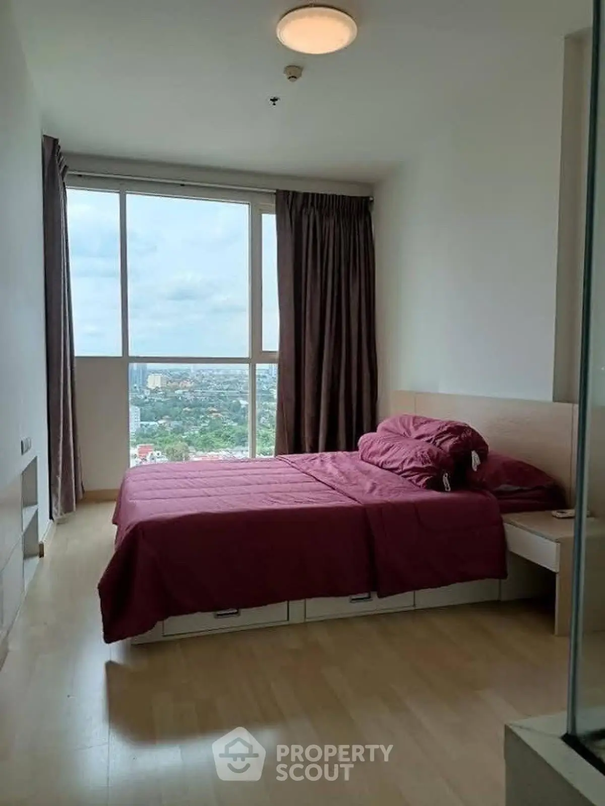 Cozy bedroom with large window offering stunning city view