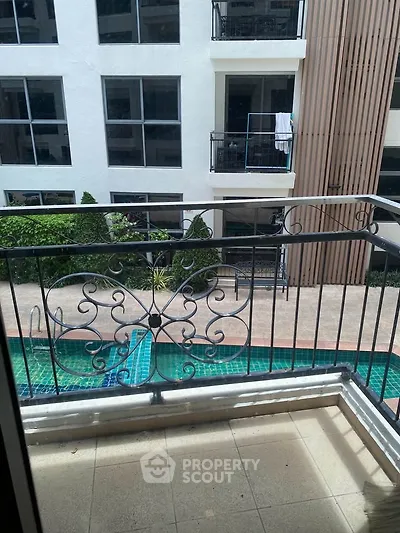 Charming balcony view overlooking a serene pool in a modern apartment complex.