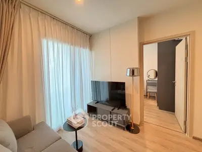 Modern living room with cozy sofa and sleek TV setup, featuring elegant curtains and wooden flooring.