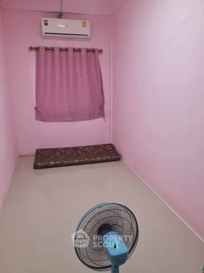 Cozy minimalist bedroom with pink walls, air conditioning, and floor mattress.