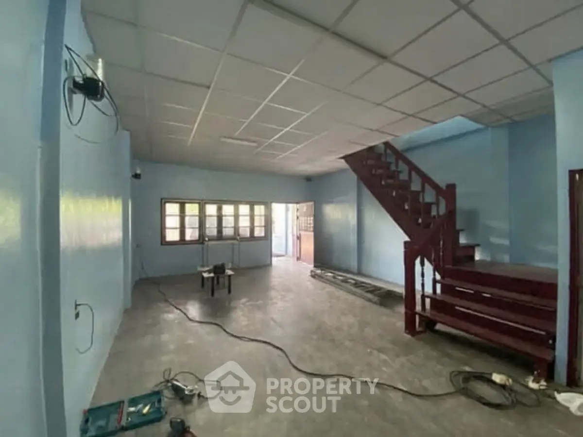 Spacious interior with staircase and large windows, ideal for customization and renovation.