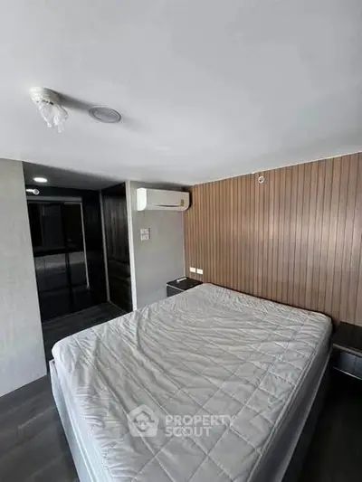 Modern bedroom with sleek design and air conditioning, featuring a comfortable bed and stylish wood paneling.