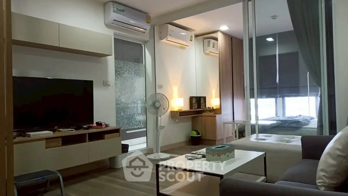 Modern living room with open layout and cozy bedroom, featuring air conditioning and stylish decor.