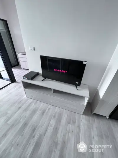 Modern minimalist living room with sleek grey flooring and contemporary wall-mounted TV unit, perfect for urban living.