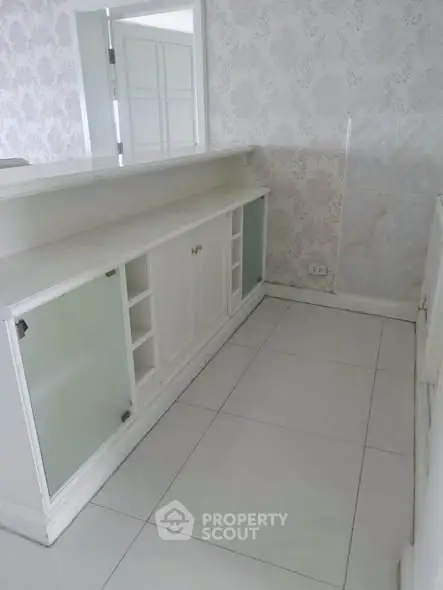 Elegant white interior with built-in storage and decorative wallpaper, perfect for modern living.