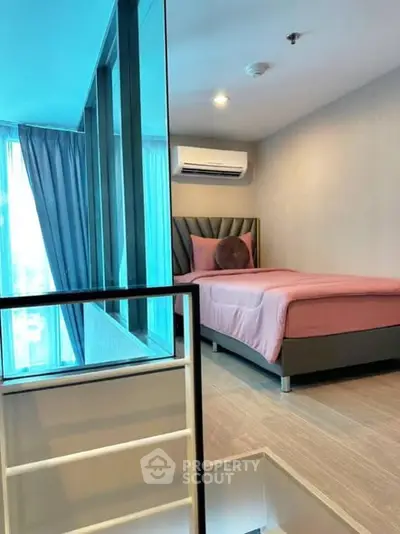 Modern bedroom with pink bedding and large window in stylish apartment.