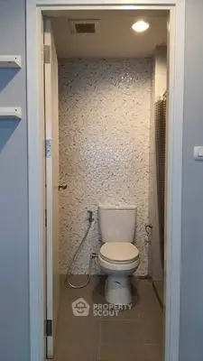 Compact bathroom with modern toilet and tiled walls in a cozy apartment.