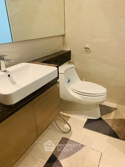 Modern bathroom with sleek fixtures and stylish design, featuring a contemporary sink and toilet.