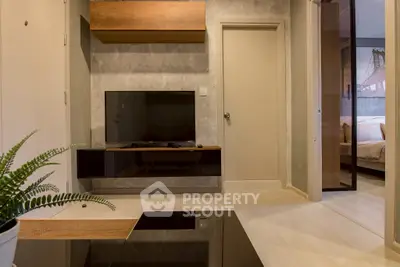 Modern living room with sleek TV setup and view into cozy bedroom