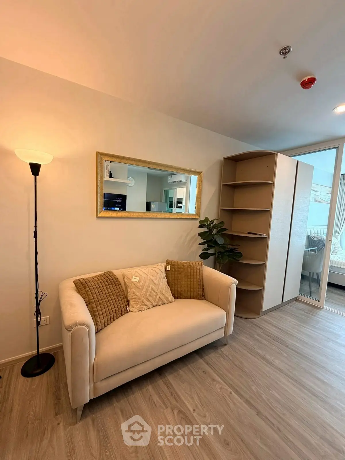 Modern living room with cozy sofa, stylish mirror, and elegant shelving unit in a bright apartment.