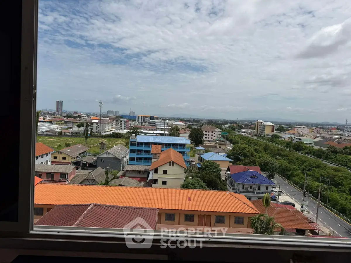 Stunning cityscape view from a high-rise window showcasing vibrant rooftops and lush greenery.
