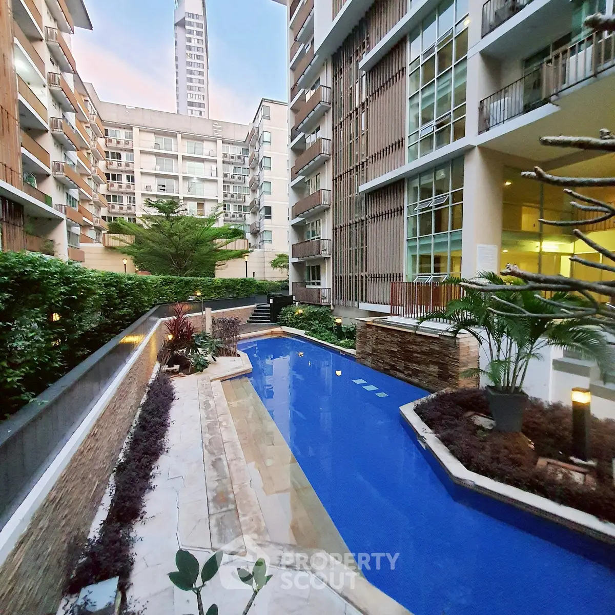 Luxurious modern apartment complex with serene pool and lush greenery