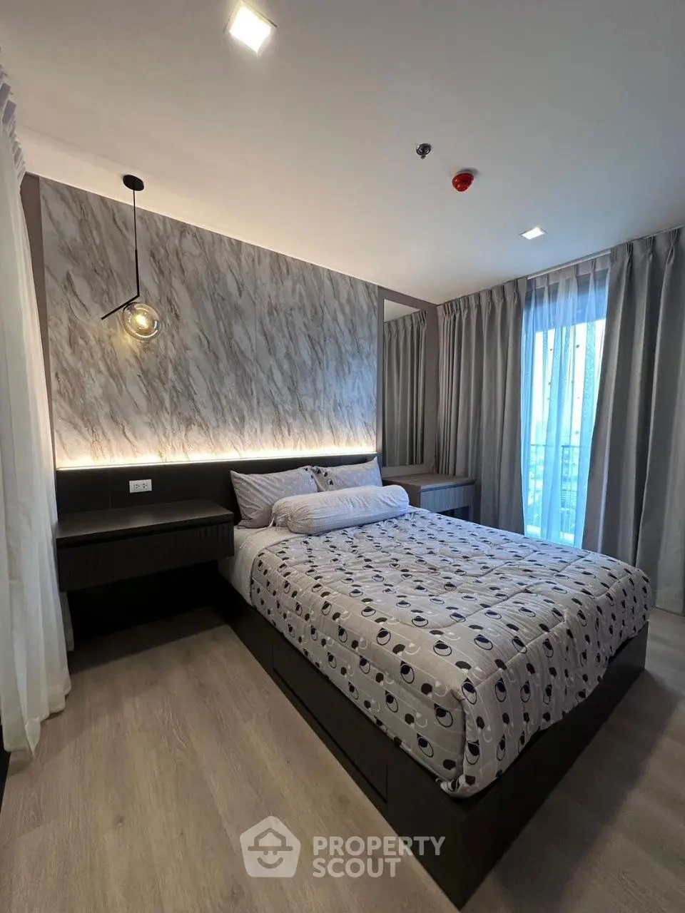Modern bedroom with stylish decor and large window offering natural light.