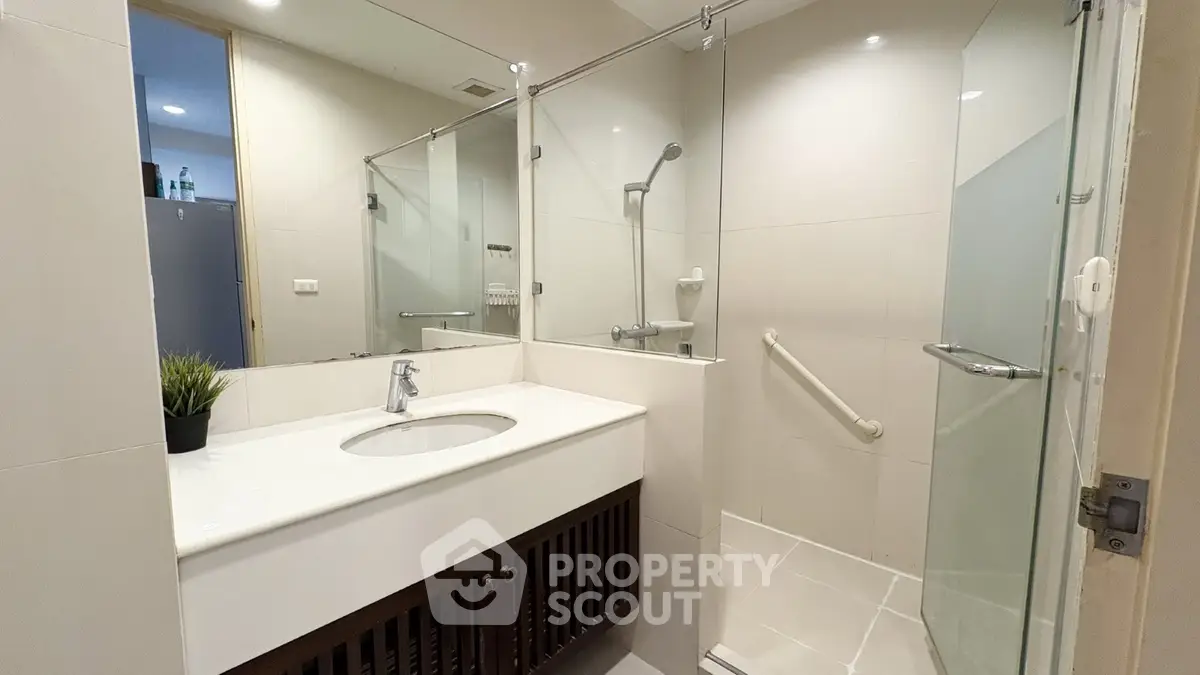 Modern bathroom with glass shower and sleek vanity in contemporary apartment.