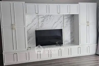 Elegant living room with built-in white cabinetry and marble accent wall
