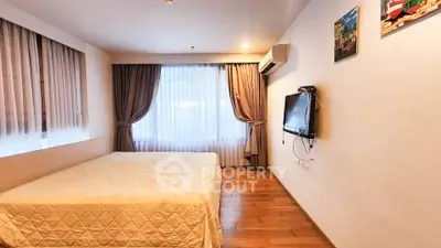 Spacious bedroom with wooden flooring and modern decor in a well-lit apartment.