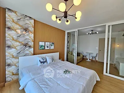 Modern bedroom with stylish decor and cozy seating area, featuring elegant lighting and wooden flooring.