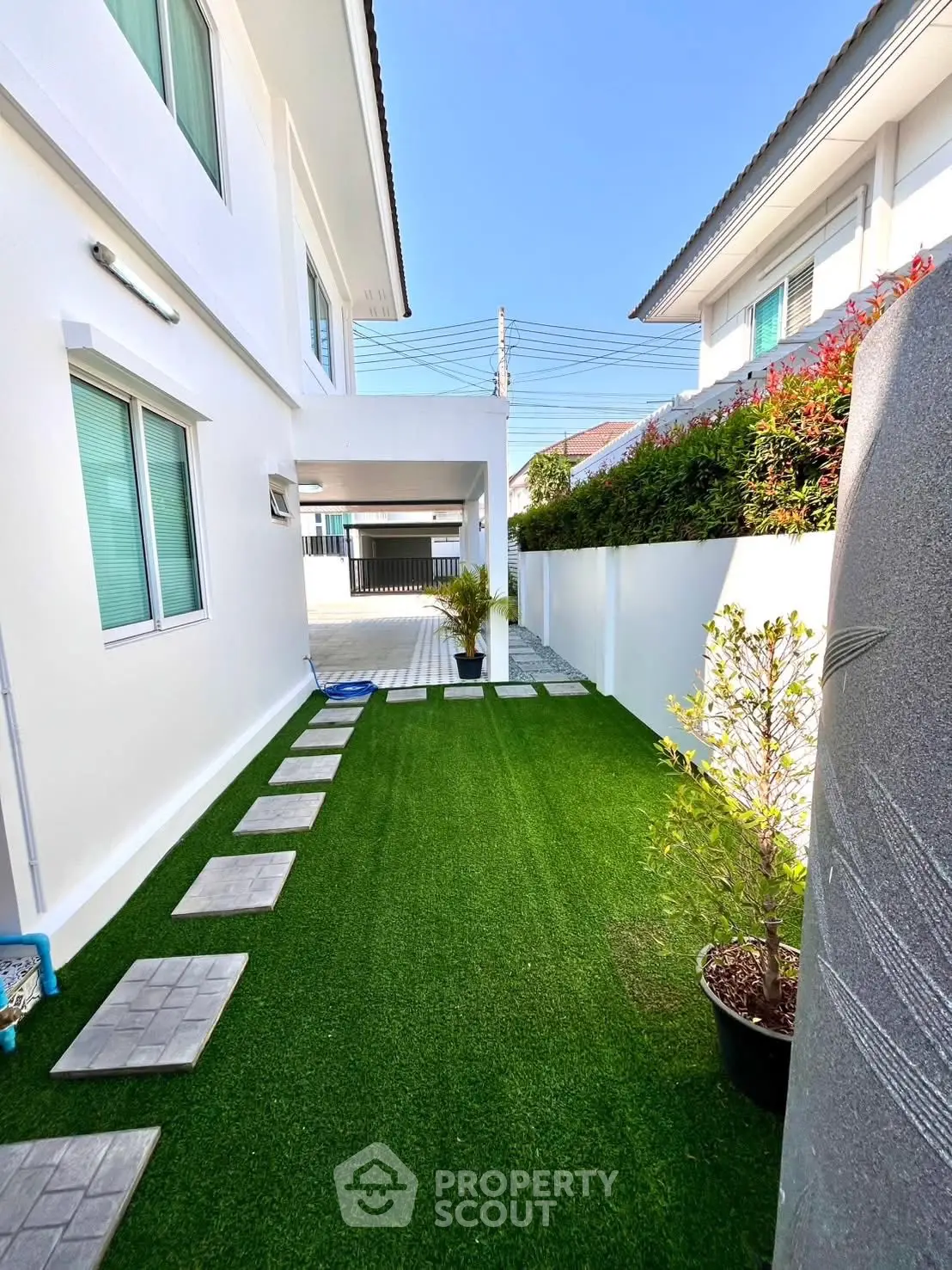 Charming side yard with artificial grass and modern exterior design, perfect for relaxation and outdoor activities.