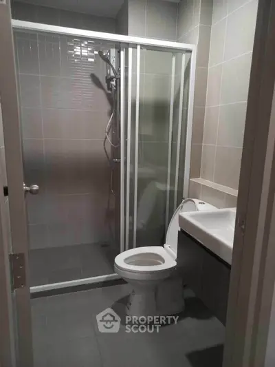 Modern bathroom with glass shower enclosure and sleek fixtures in a contemporary apartment.