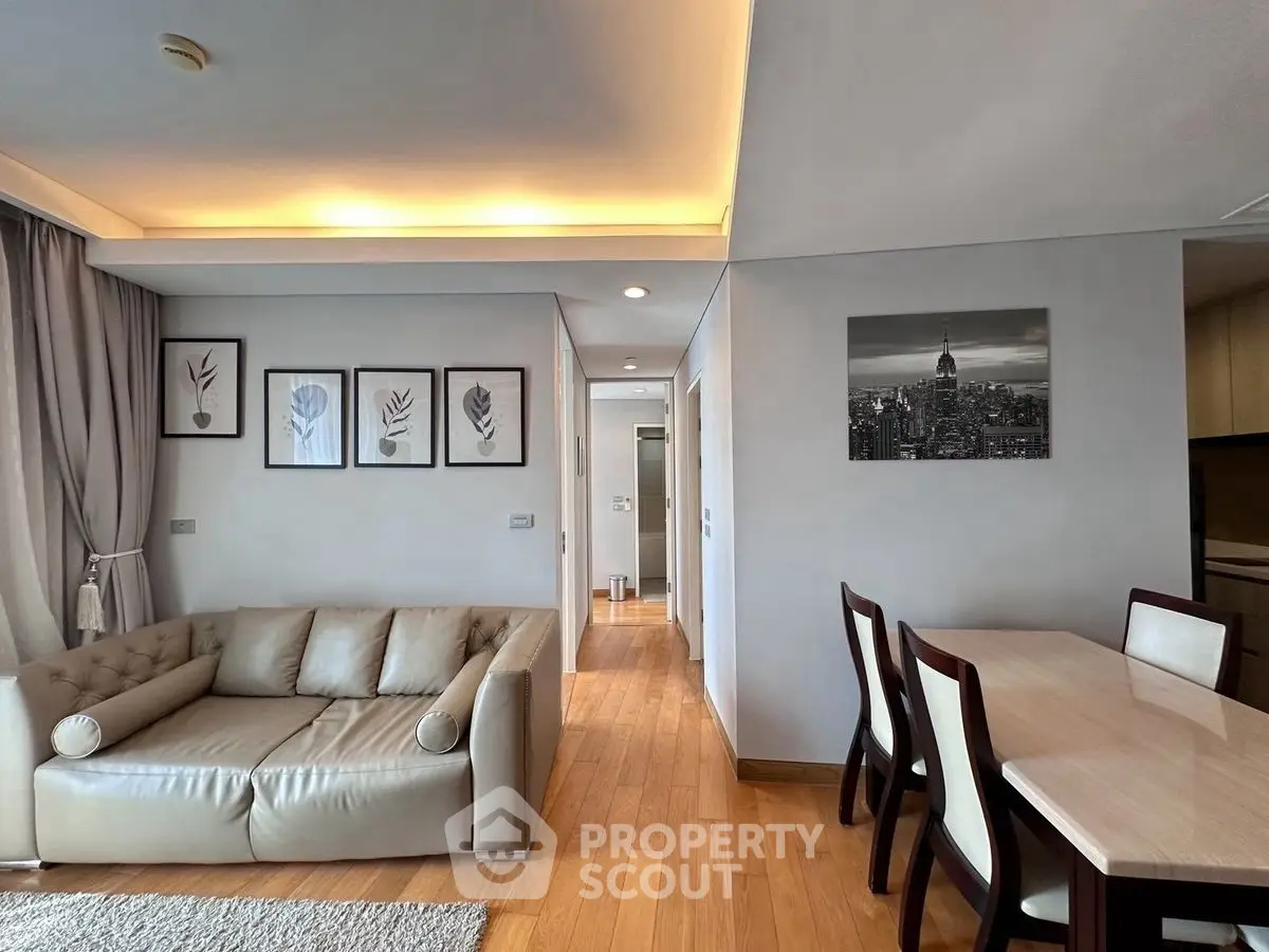 Modern living room with elegant decor and dining area, featuring stylish artwork and cozy seating.