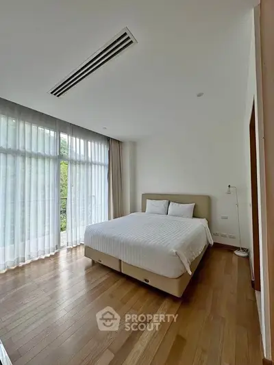 Spacious bedroom with large windows and elegant wooden flooring