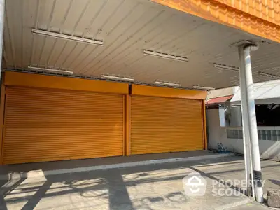 Commercial property with orange shutters and covered parking area.