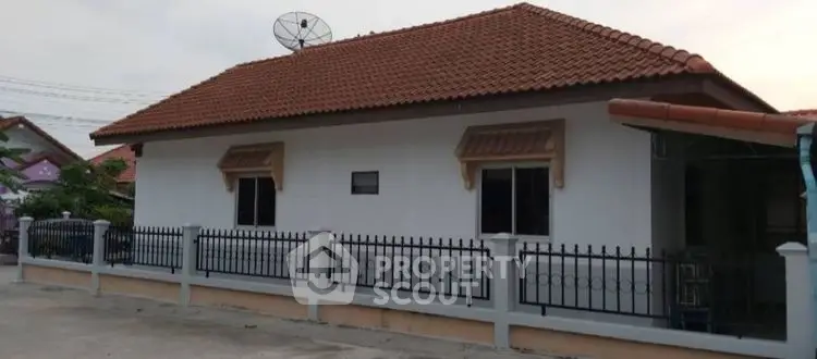 Charming single-story house with tiled roof and fenced yard in a serene neighborhood.